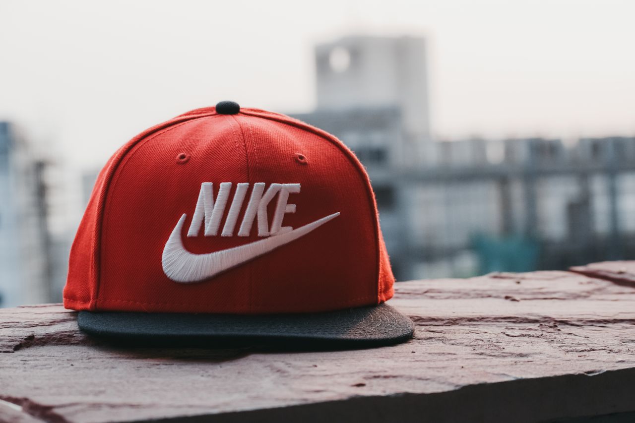 our-services-01 Red cap with logo on a rooftop against an urban cityscape backdrop in daylight.