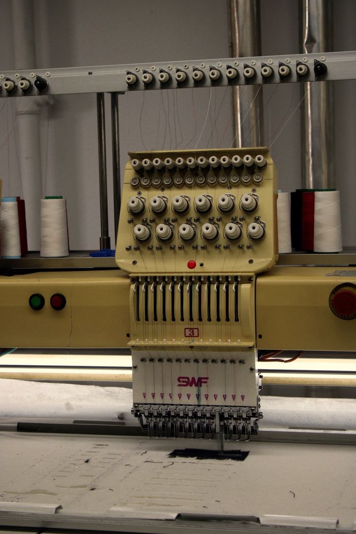 Close-up of a modern industrial embroidery machine with spools of thread for textile production.