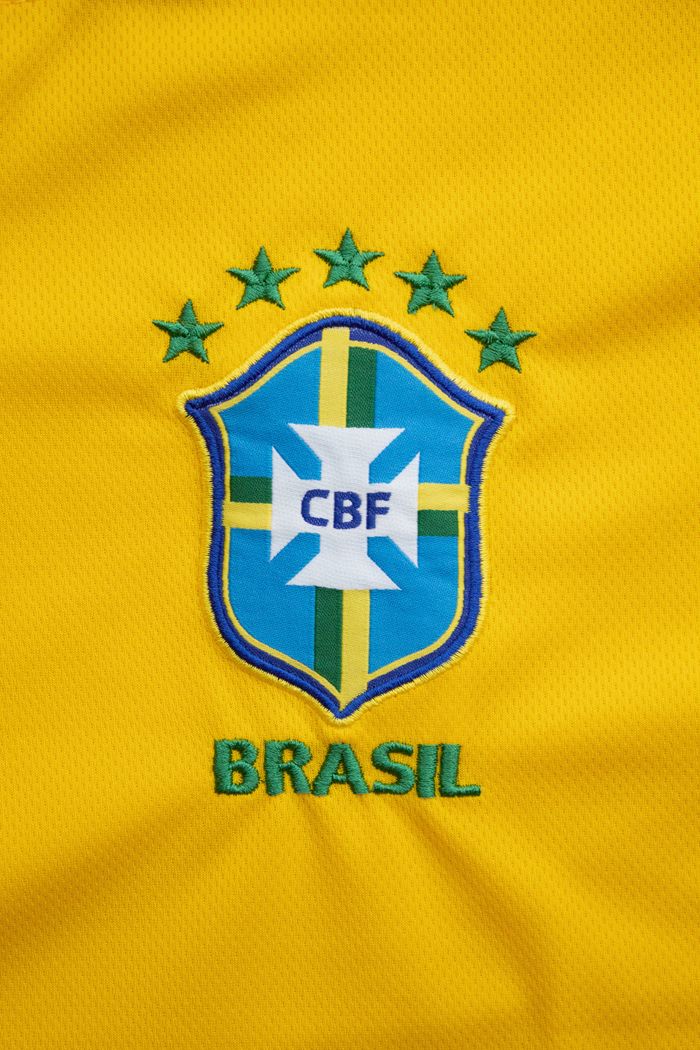 our-services-06 Close-up of the Brazilian football team emblem on a vibrant yellow jersey.