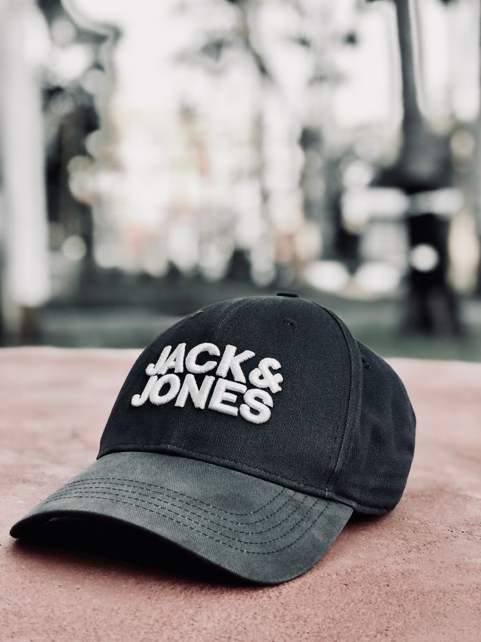 our-services-03 Close-up of a black cap with JACK & JONES logo on a sunny day outdoors.