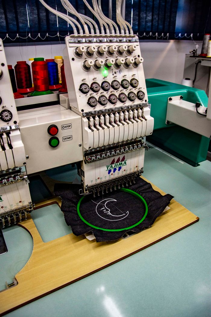 High-quality embroidery machine stitching fabric in an industrial setting in Apucarana, Brazil.