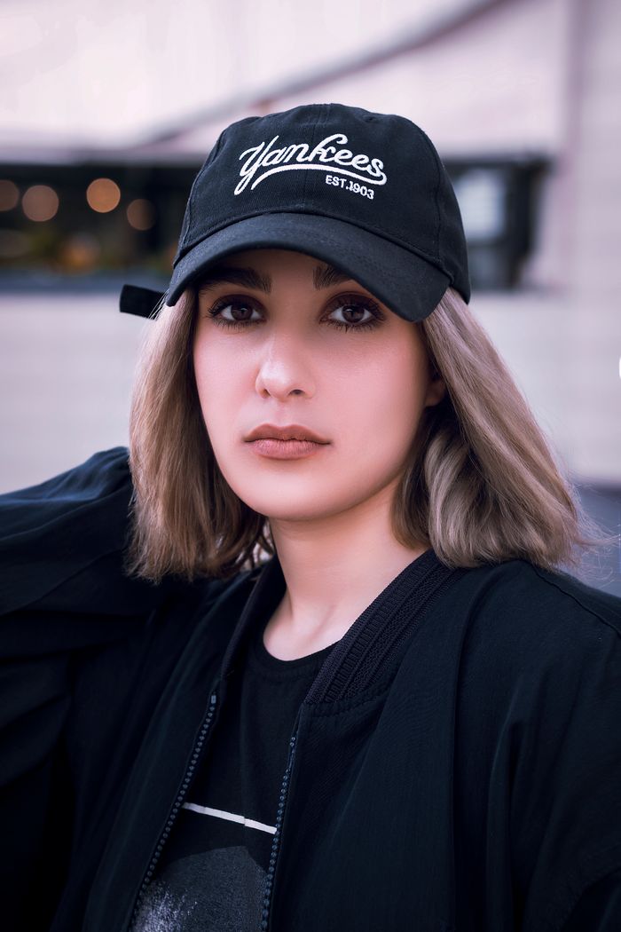 our-services-04 Stylish young woman in a Yankee cap posing in Tehran's urban setting, exuding modern fashion vibes.
